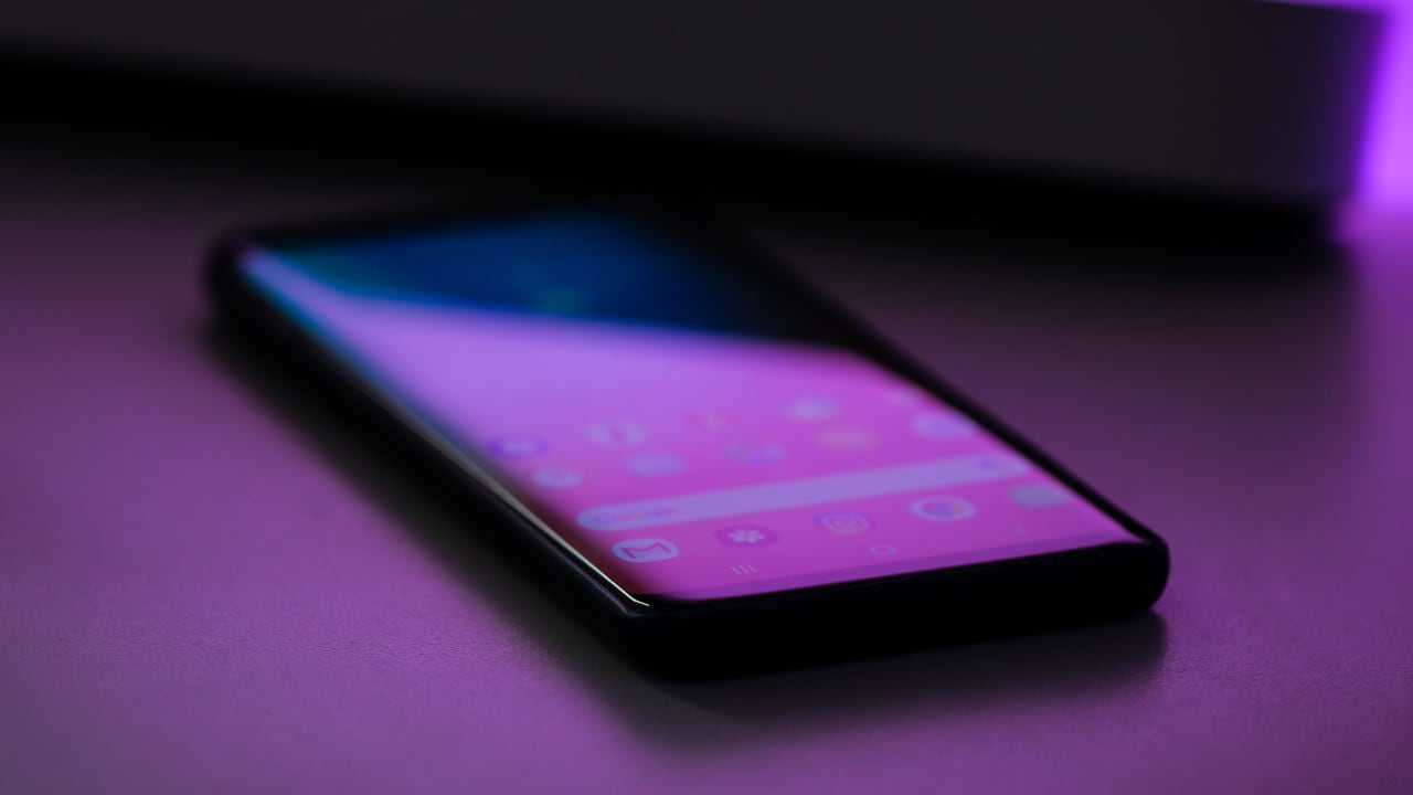 Photo of a phone sitting on a desk with neon colors